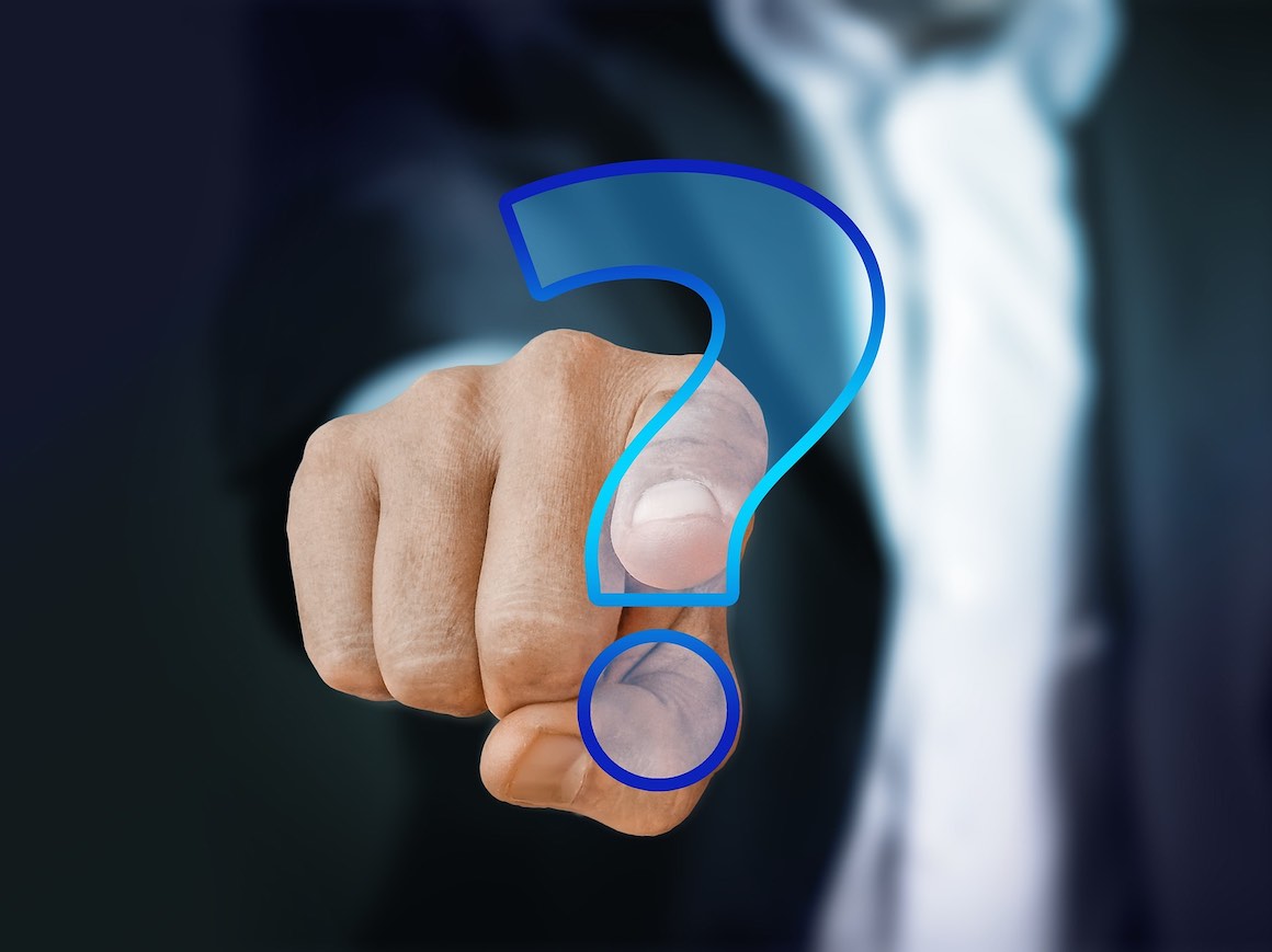 Image of suited person pointing to a question mark
